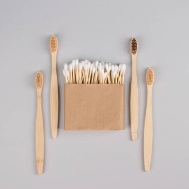 Kraft kağıt kutusunda pamuk tomurcukları ve açık gri arka planda doğal bambu diş fırçaları - sıfır atık banyo esasları. Sürdürülebilir yaşam tarzı konsepti. Model ve kopyalama alanı, kare bileşimi