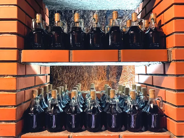 地元のワイナリーで石の棚に赤ワインボトル 地元のワイン店で伝統的な自家製ワインやアルコールフルーツドリンク ラベルのないワインボトル フード ドリンク観光のコンセプト モックアップイメージ — ストック写真