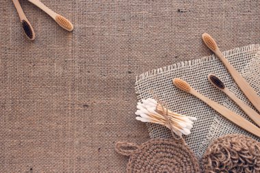 Doğal tuvalet aletleri, sürdürülebilir sıfır atık ve yaşam tarzı konsepti. Ahşap diş fırçaları, bambu çubukları ve kumaş arka planında fotokopi alanı olan el yapımı jüt vücut yıkama giysileri. Model