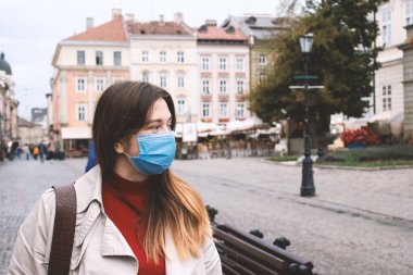 Sokakta tek kullanımlık koruyucu maske takan güzel bir genç kadın. Pandemik önleme ve yeni normal kavram. Hava kirliliği ve mevsimsel salgın konsepti