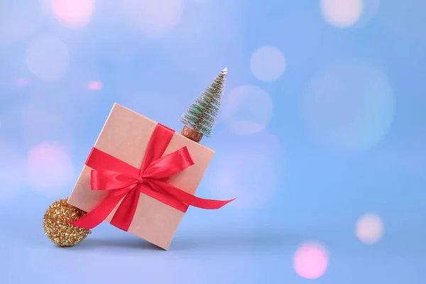 Caixa de presente com arco vermelho e decorações de árvore de Natal em fundo azul festivo com bokeh borrado e copyspace para o seu texto. Conceito de celebração de Natal ou Ano Novo — Fotografia de Stock