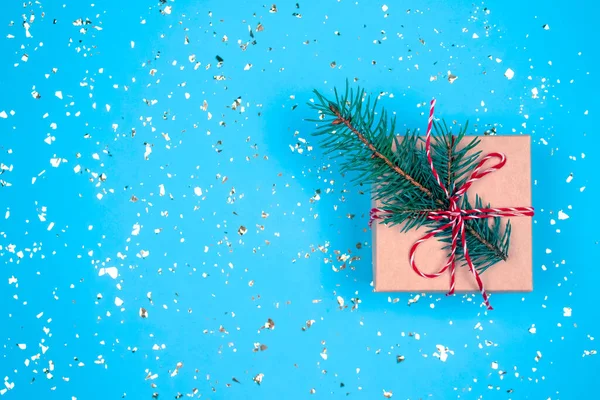 Caixa de presente com arco vermelho e galho de árvore de Natal no fundo azul festivo com brilhos dourados ao redor e espaço para o seu texto. Estilo leigo plano. Conceito de celebração de Natal ou Ano Novo — Fotografia de Stock