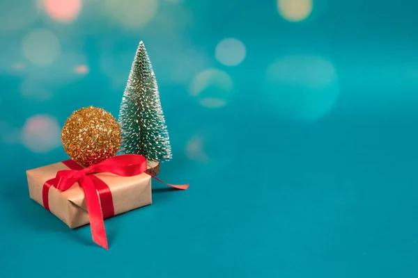 Composição de Natal e Ano Novo com árvore de Ano Novo, decorações de bola de Natal dourado, caixa de presente com arco vermelho e luzes bokeh no fundo verde com copyspace. Foco seletivo, lugar para texto — Fotografia de Stock