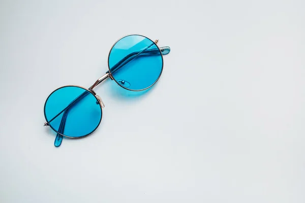 Niebieskie okulary. Letni zestaw na relaks w sezonie gorącym. Morze, piasek i słońce. Patrząc przez niebieskie okulary. — Zdjęcie stockowe