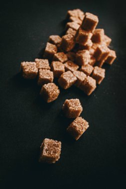 Siyah arka planda kahverengi kamış şekeri. Durgun hayat. 