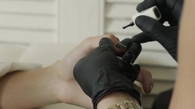 Siyah lateks koruyucu eldivenlerin ustası fırçayı siyah cila ile tüpe batırıyor. Güzellik Salonu, Manikür