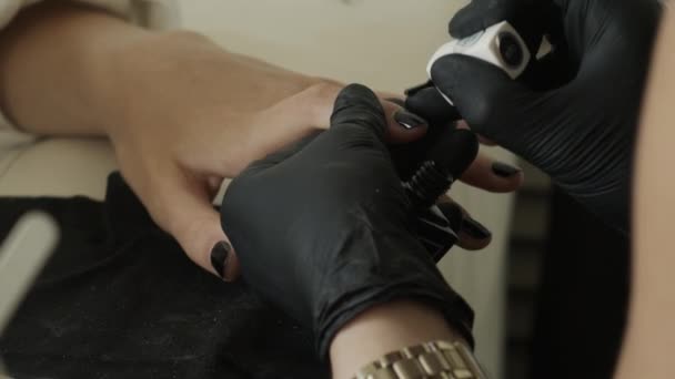 El maestro en guantes protectores de látex negro sumerge un cepillo en un tubo con un barniz negro. Salón de belleza, Manicura — Vídeo de stock