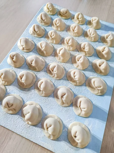 Rauwe zelfgemaakte knoedels op een blauw bord. Vormen van dumplings. — Stockfoto