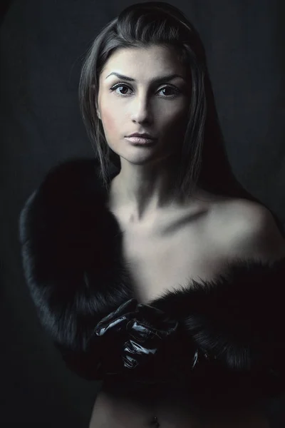 beautiful Oriental girl with almond eyes in furs on dark background