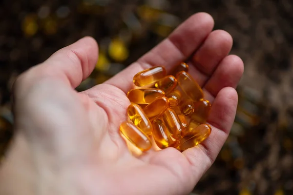 many capsules of gold color lies in the hand