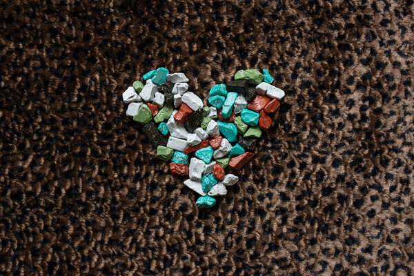 знак сердца выложен цветными конфетами на коже леопарда
