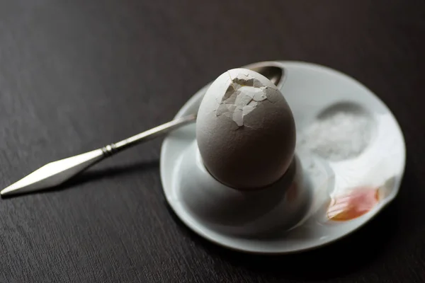 Oeuf bouilli cassé avec cuillère, stand et sel sur fond sombre — Photo