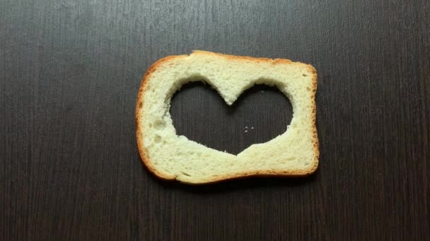 Een Stuk Brood Gesneden Hart Tegen Een Donkere Plank — Stockvideo