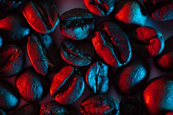 Uma dispersão de grãos de café para o fundo iluminado com néon — Fotografia de Stock