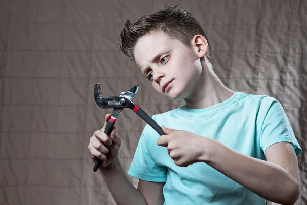 Un chico con una llave inglesa y ojos sorprendidos reparaciones — Foto de Stock