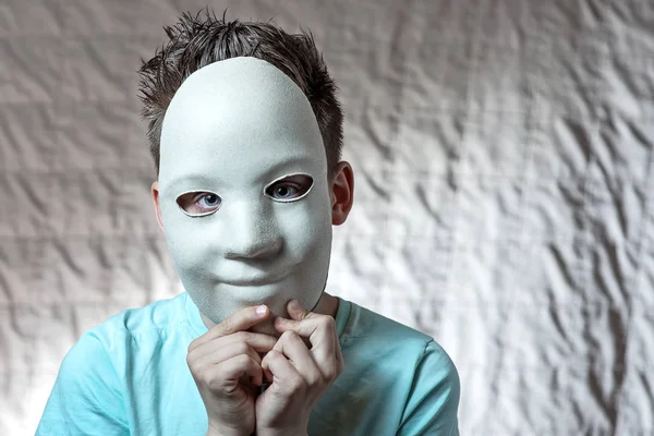 Niño en una camiseta ligera apoyado en la cara de una máscara blanca — Foto de Stock