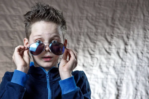Niño en una chaqueta deportiva azul y gafas de sol — Foto de Stock