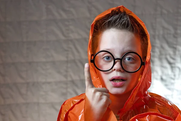 Niño en un impermeable naranja brillante y gafas redondas se refugió de la lluvia — Foto de Stock