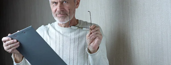 Homem de cabelos grisalhos em roupas leves e óculos entra em um contrato no papel — Fotografia de Stock