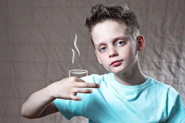 Niño en una camiseta ligera sosteniendo una taza pintada de té o café — Foto de Stock