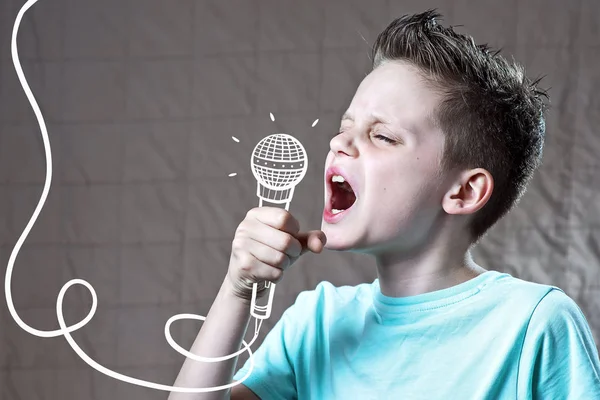 Dreng i en blå t-shirt synger meget højt ind i en malet mikrofon - Stock-foto