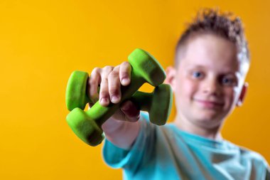 sarı bir arka plan üzerinde dumbbells ile parlak bir t-shirt bir çocuk