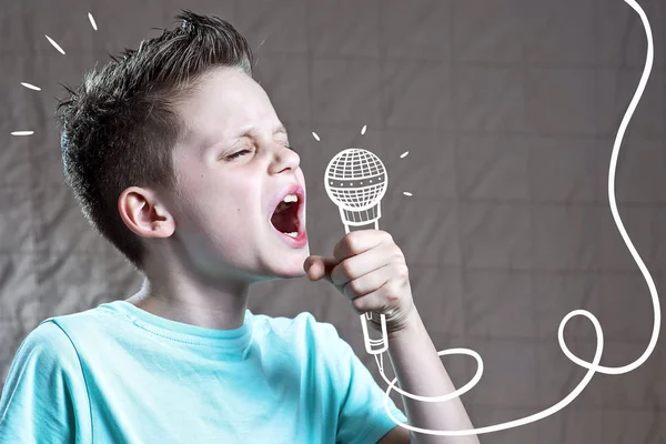 Dreng i en blå t-shirt synger meget højt ind i en malet mikrofon - Stock-foto