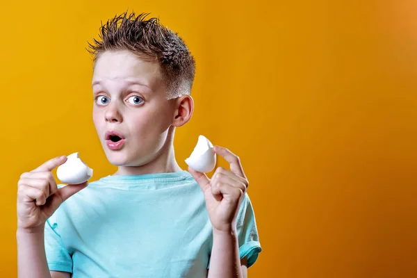 Munter dreng i en let t-shirt med et brudt æg på en farvet baggrund - Stock-foto