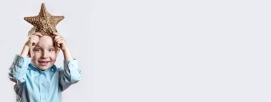 beyaz bir arka plan üzerinde bir denizyıldızı tutan hafif bir t-shirt çocuk