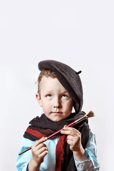 Dreng kunstner i sort baret og maling børste i hånden på en lys baggrund - Stock-foto