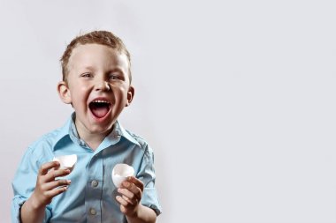 yumurtadan bir kabuk tutan ve hafif bir arka plan üzerinde gülümseyen hafif bir gömlek çocuk