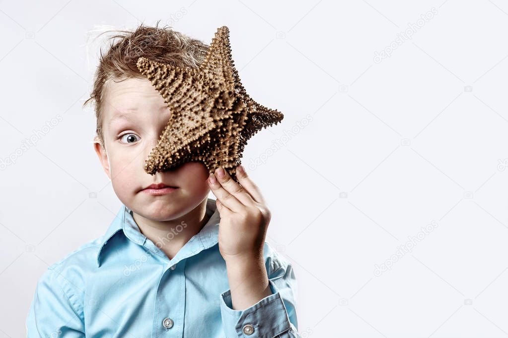 boy in a light t-shirt holding a starfish on a white background
