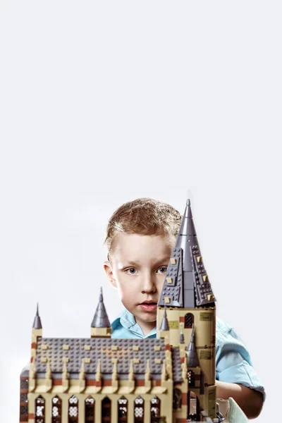 Boy in a light shirt looks out from the constructed lock of the designer — Stock Photo, Image