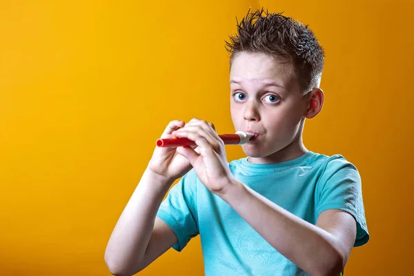 Un niño con una camiseta ligera jugando en una pipa sobre un fondo de color — Foto de Stock