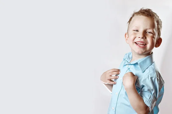 Un niño feliz sonriente en camisa azul sobre fondo claro — Foto de Stock