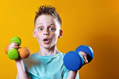 sarı bir arka plan üzerinde dumbbells ile parlak bir t-shirt bir çocuk