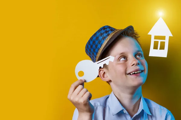 Um menino alegre com uma casa de papelão e uma chave em um fundo colorido brilhante — Fotografia de Stock