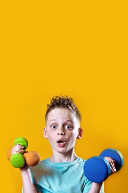 sarı bir arka plan üzerinde dumbbells ile parlak bir t-shirt bir çocuk