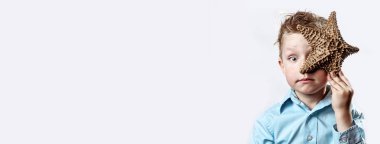 beyaz bir arka plan üzerinde bir denizyıldızı tutan hafif bir t-shirt çocuk