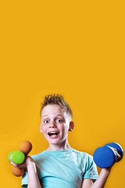 sarı bir arka plan üzerinde dumbbells ile parlak bir t-shirt bir çocuk