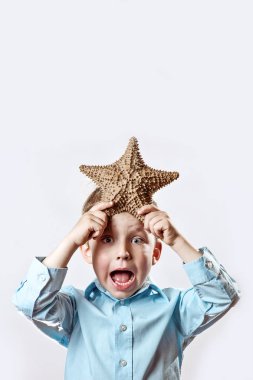 beyaz bir arka plan üzerinde bir denizyıldızı tutan hafif bir t-shirt çocuk