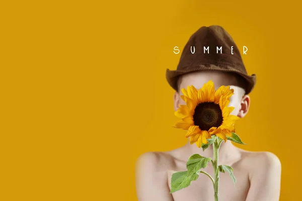 Літній хлопчик з жовтим соняшником закриває обличчя — стокове фото