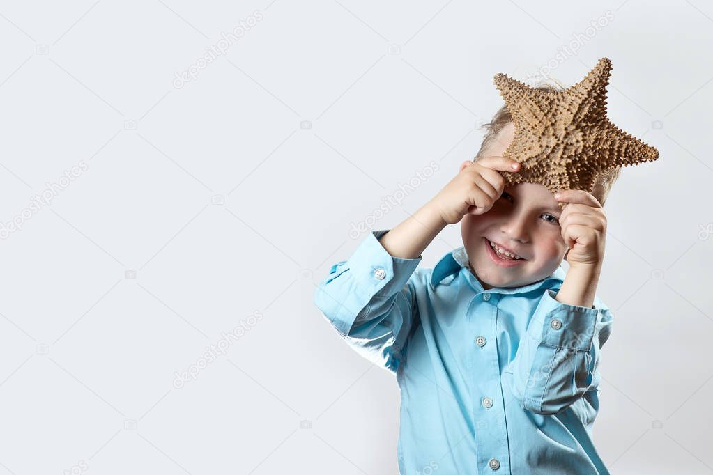 boy in a light t-shirt holding a starfish on a white background