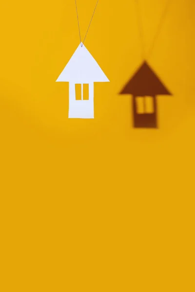 Mały dom wykonany z tektury rzuca cień na jasnym kolorowym tle — Zdjęcie stockowe