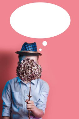 parlak renkli arka planda yüzünün önünde bir buket tutan bir şapka adam