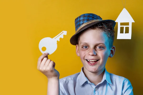 Веселий хлопчик з картонним будинком і ключем на яскравому кольоровому фоні — стокове фото
