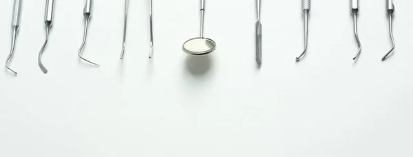 Una serie de herramientas dentales colocadas planas sobre un fondo claro — Foto de Stock