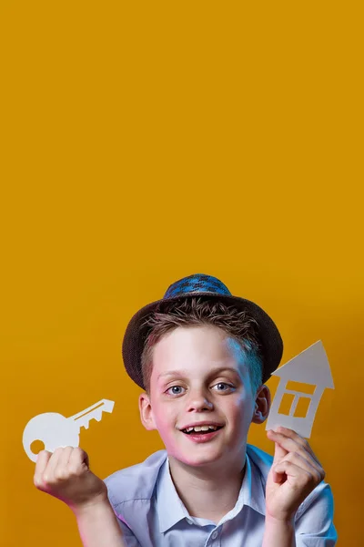 A cheerful boy with a cardboard house and a key on a bright colored background — Stock Photo, Image