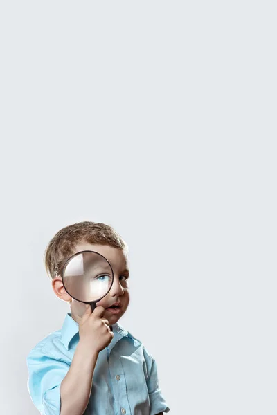 Băiat într-un tricou ușor uitându-se într-o lupă mare — Fotografie, imagine de stoc