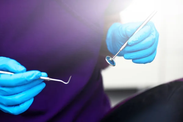 In het kantoor van de tandheelkundige kliniek. De arts houdt gereedschappen voor het onderzoek van de tanden in steriele handschoenen. — Stockfoto